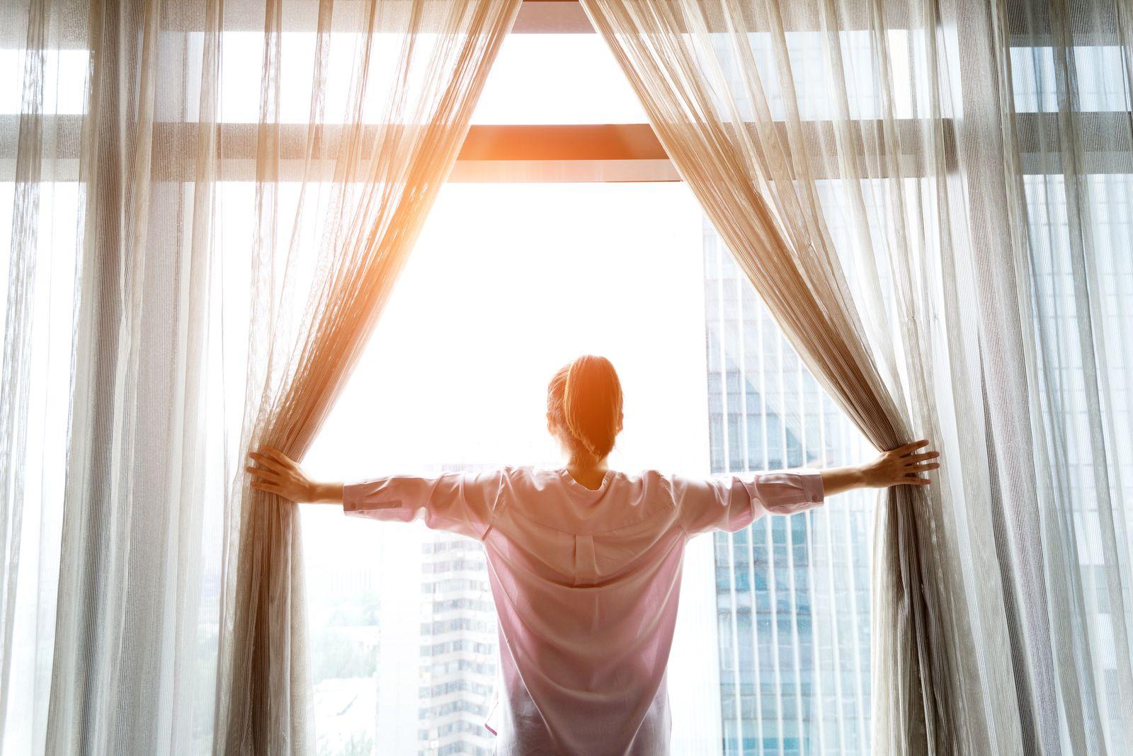 A guest opening the curtains on a bright morning