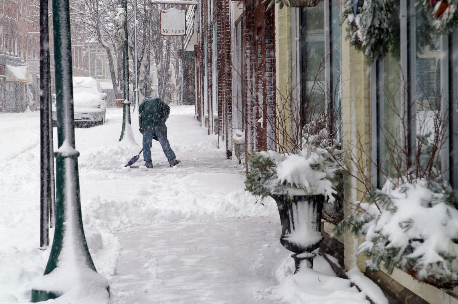 Someone clearing snow from a pavement outside a row of guest houses